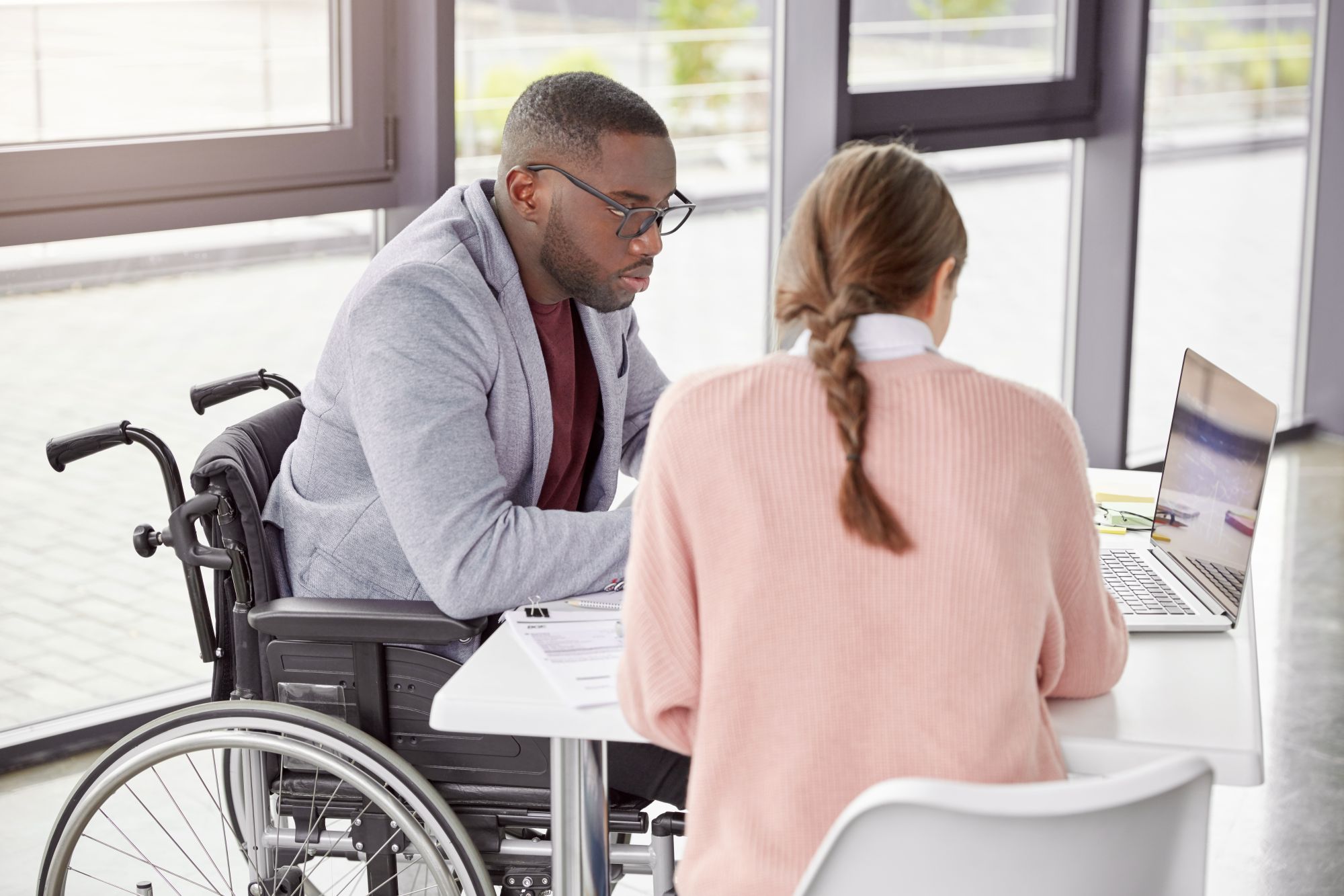 Man with disability reviews options on a computer while seated at a table with a woman